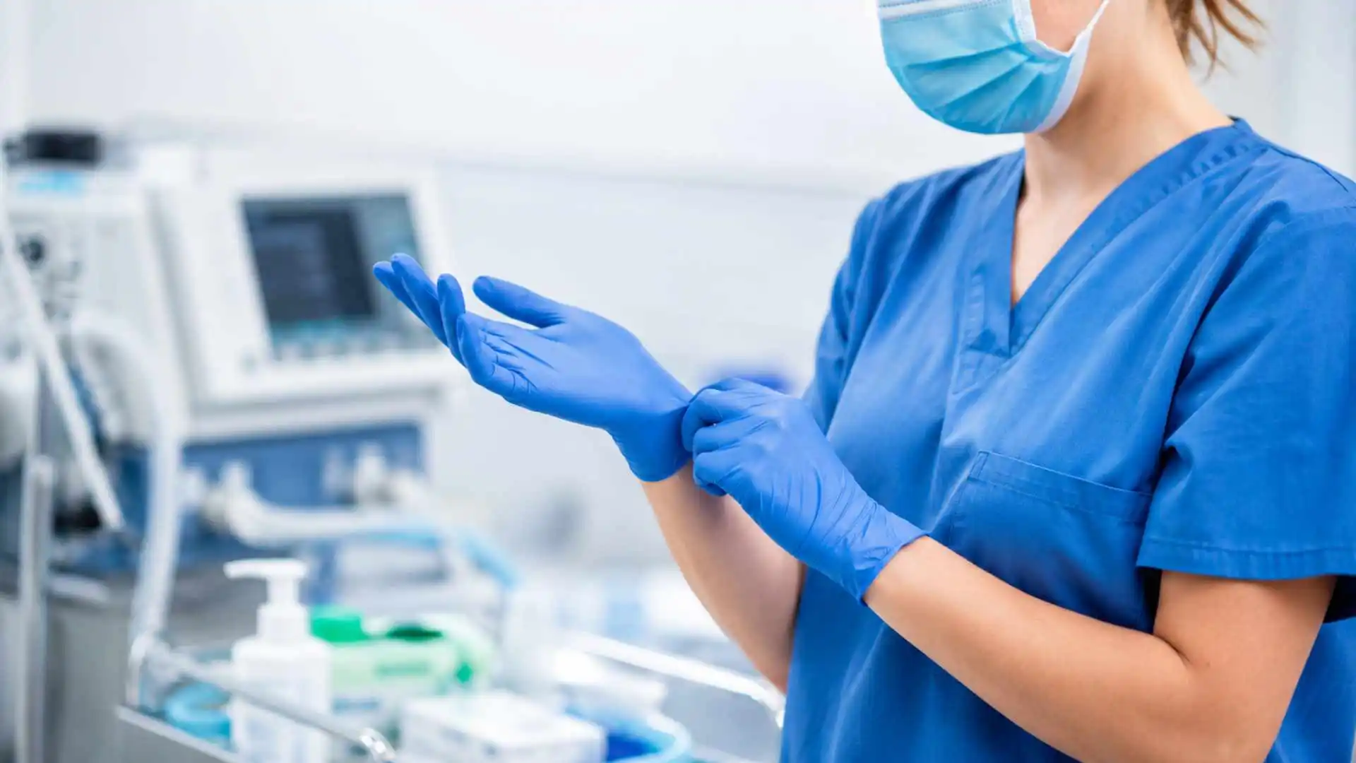 Pflegefachkraft oder Mediziner mit blauen Nitrilhandschuhen bei professioneller Anwendung